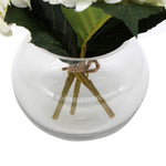 Clear glass vase with decorative sticks and greenery on a white background