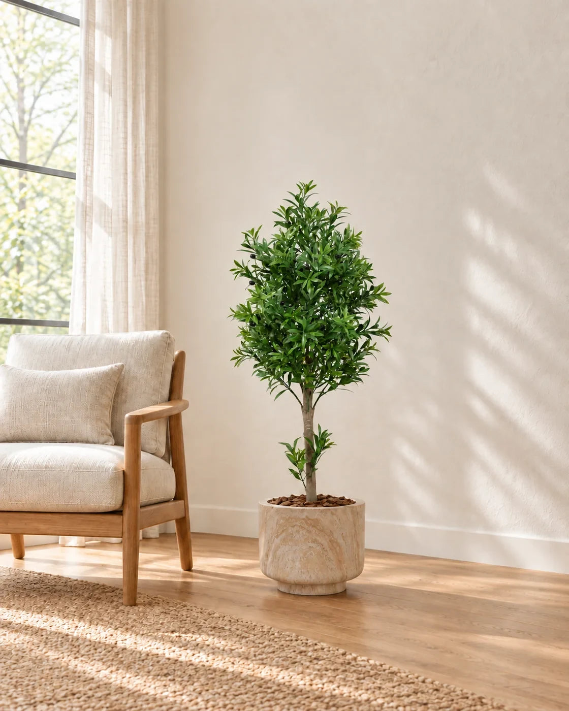 Artificial manicured olive tree styled beside an armchair in a decorative planter; planter not included; AI-generated styling image
