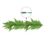 Green artificial fern leaf with a close-up of its stem on a white background