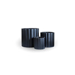 Three black ribbed cylindrical planters on a white background