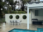 Outdoor patio area with dining set by a poolside, featuring a white pergola and greenery.