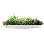 Artificial green plant arrangement in a white planter on a white background