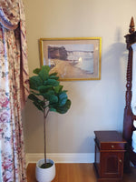 Room interior with a potted plant, framed picture on the wall, and wooden furniture.