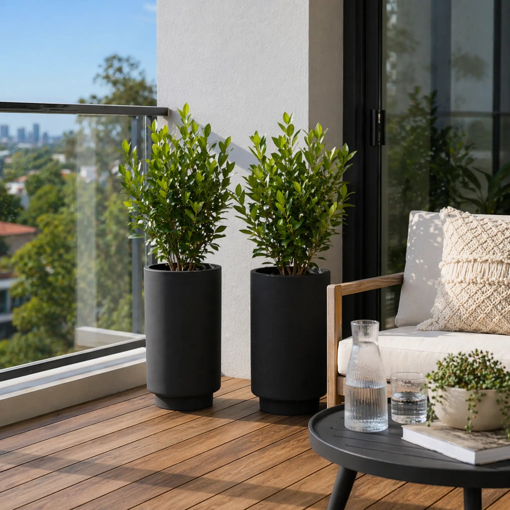 Two potted plants on a wooden deck with a view of a cityscape.