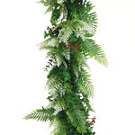 Artificial greenery garland with leaves and flowers on a white background