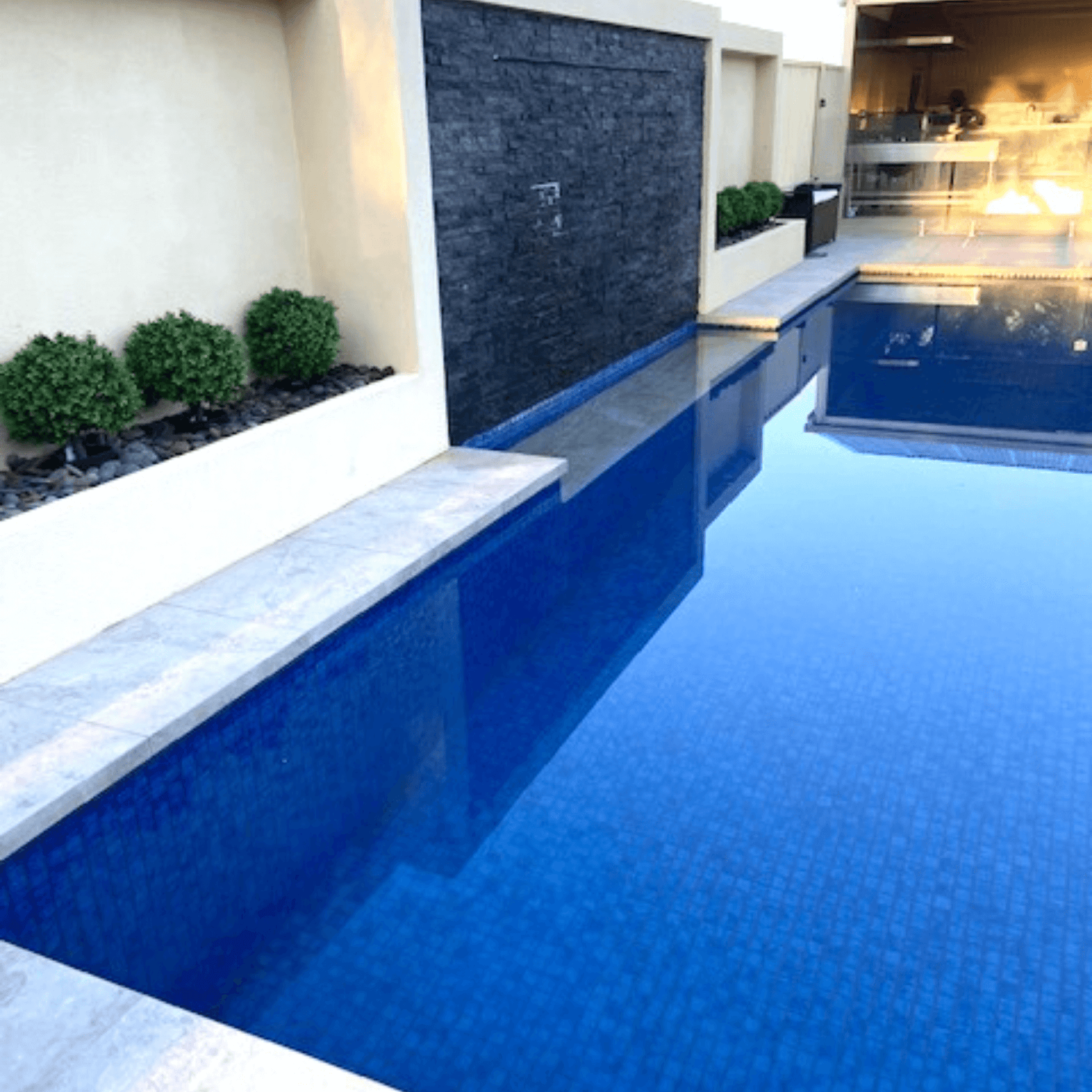 Modern outdoor pool with water feature and garden area